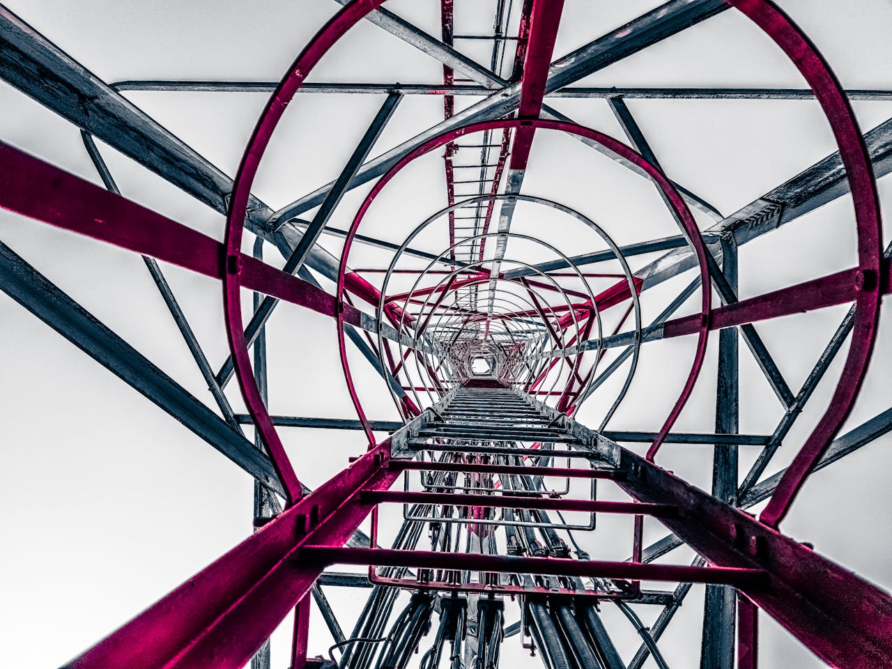 Low angle view inside an industrial tower structure showing its geometric patterns and framework.