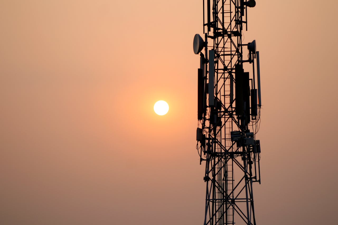 A striking silhouette of a communication tower against a vibrant sunset sky.