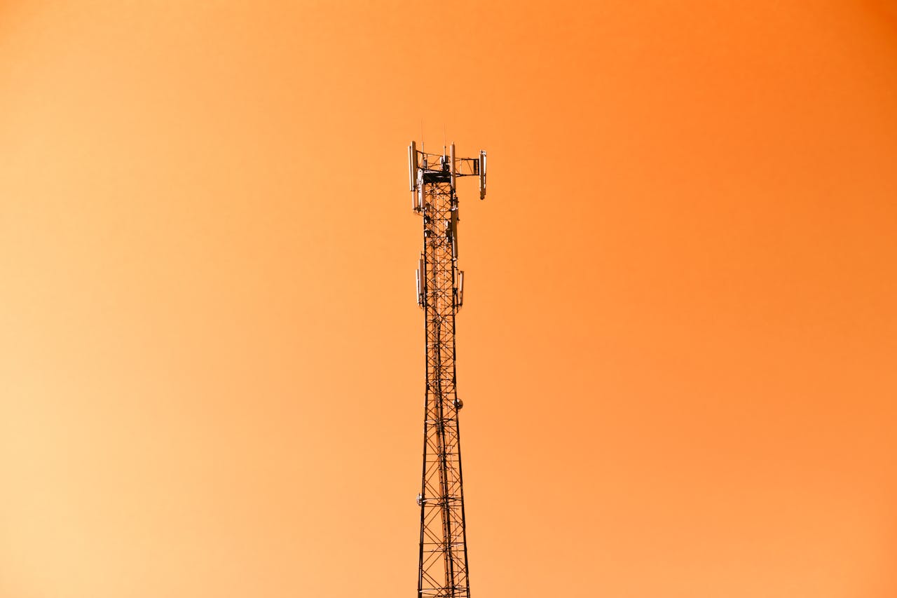Radio mast silhouetted against a vibrant orange sky in Adana, Türkiye.