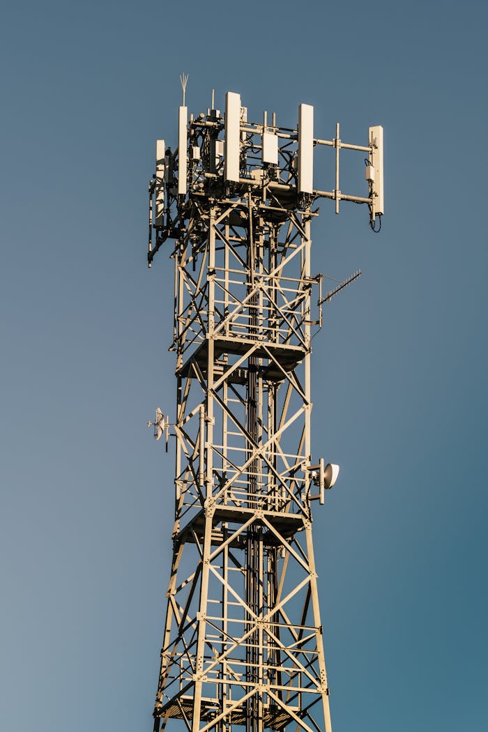 Close-up of a telecom tower with antennas and clear blue sky background.