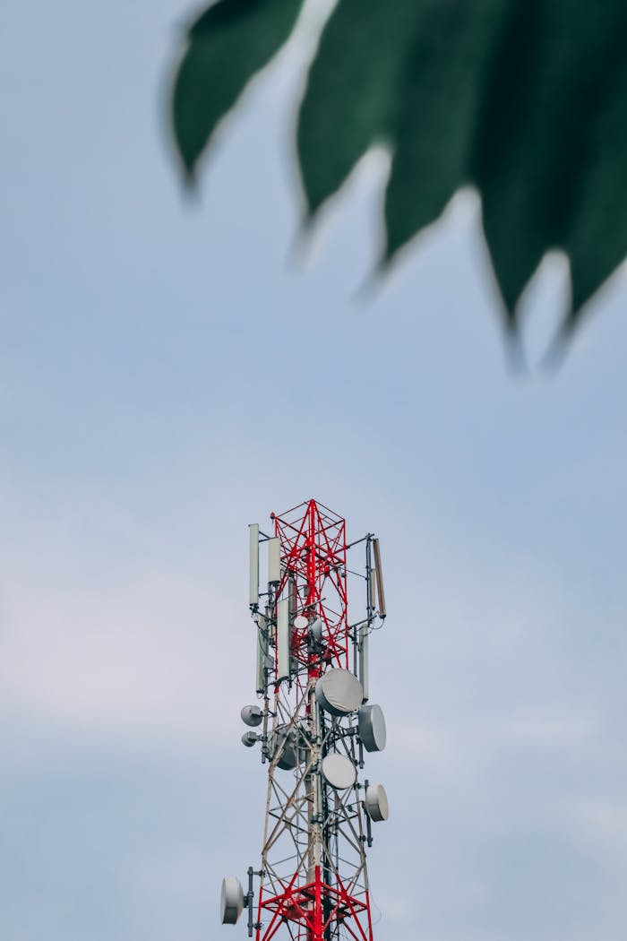 A telecommunications tower with antennas and dishes against a clear blue sky in Ulipur, Bangladesh.